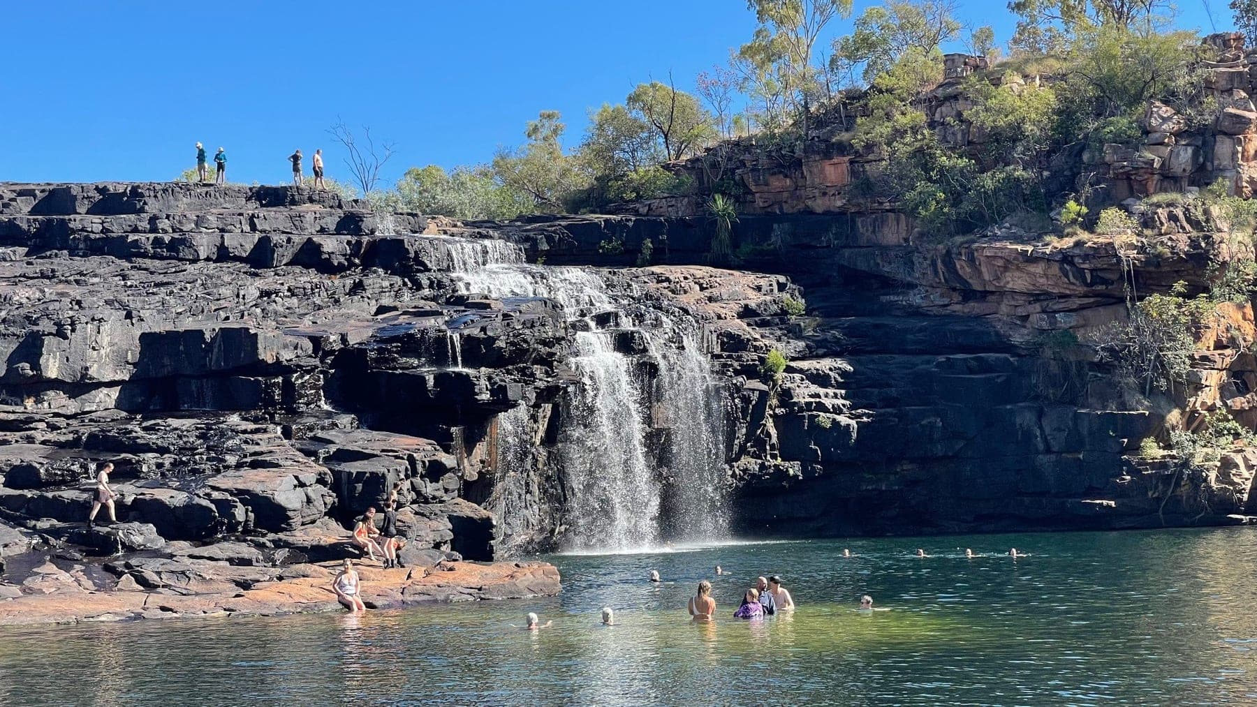Guests swimming in the pool at the base of Manning Falls
